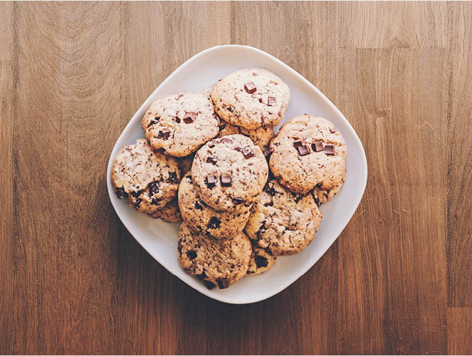 chocolate-chip-cookies-white-plate-wood-table-flat-lay
