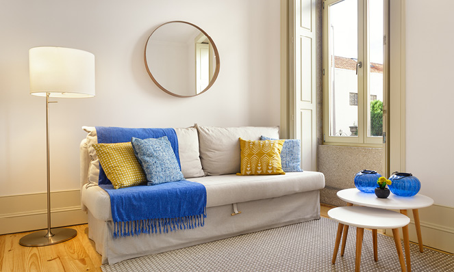 tan-living-room-blue-throw-blanket-circle-mirror-end-tables-lamp-french-door-windows