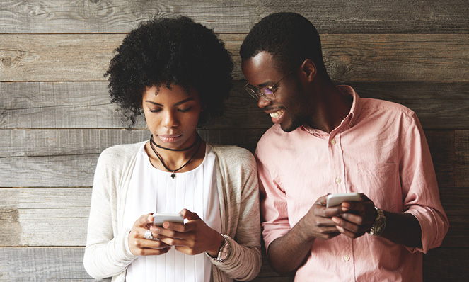 millennials-holding-phones-standing-against-wood-wall