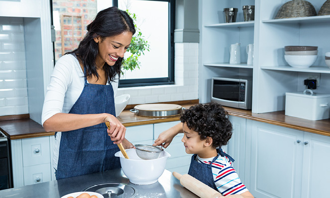 mother-heling-child-bake-in-bright-kitchen