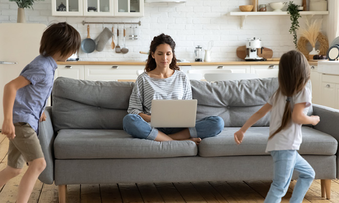 mother-working-on-laptop-young-children-running-around