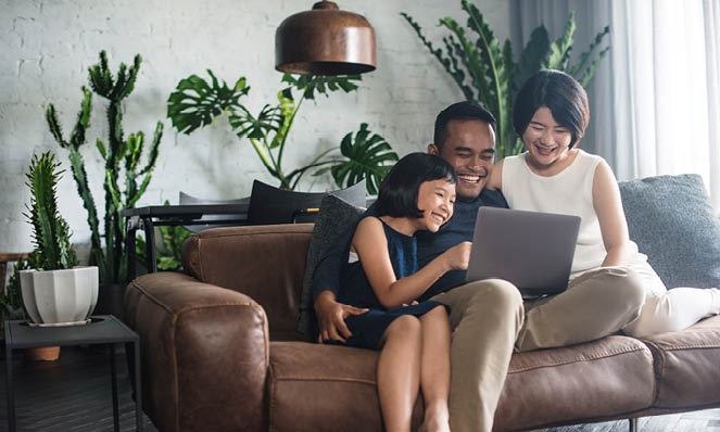 asian-american-family-sitting-on-leather-couch-with-laptop-