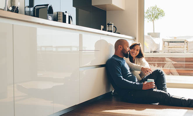 man-holding-drink-with-female-in-kitchen-sitting-on-floor