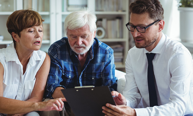 older-couple-with-advisor-looking-at-clipboard