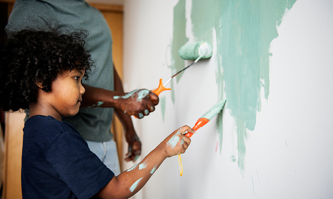 young-child-painting-wall-green-with-parent