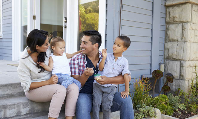 young-family-four-outside-home-laughing