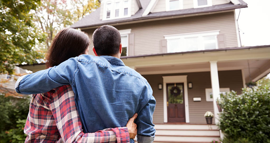 couple-looking-at-home-green-trees-front-door