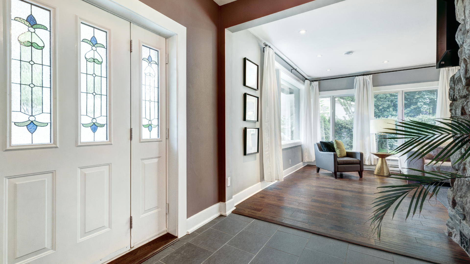 Bright home entryway and living space with hardwood floors, large windows and a white front door.