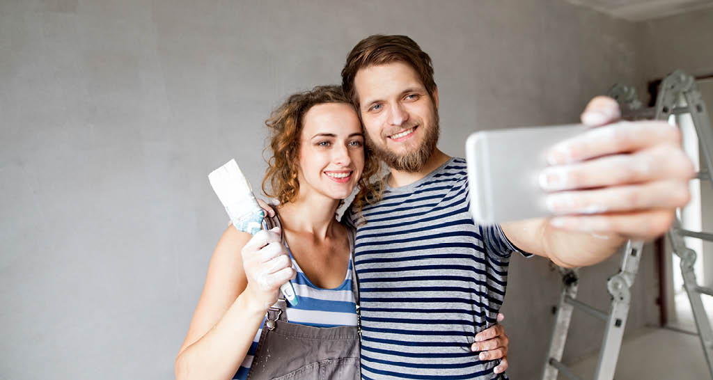 smiling-millennial-couple-taking-selfie-home